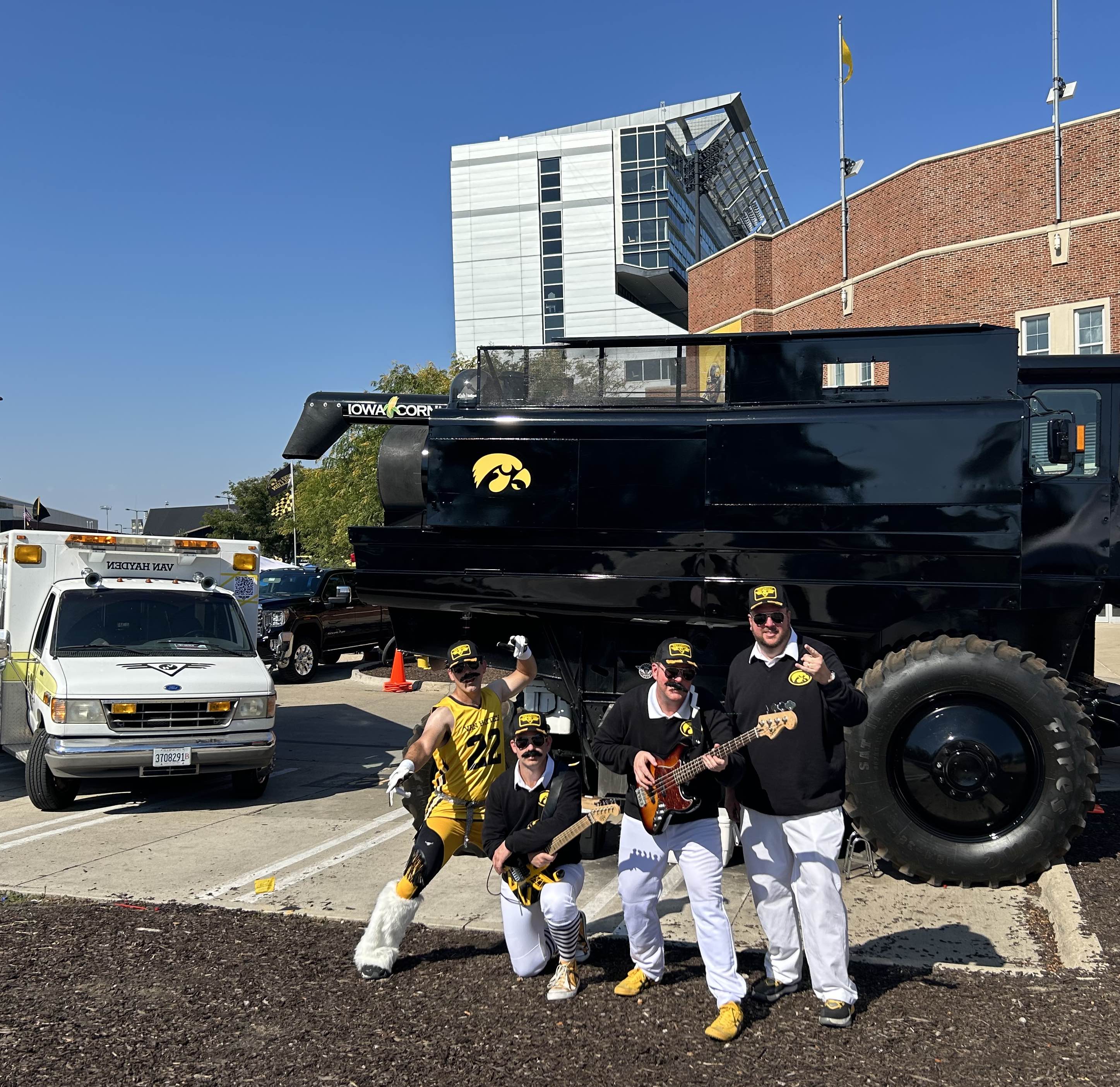 Van Hayden Band posing for a photo next to Kinnick Stadium and a Hawkeye decorated combine