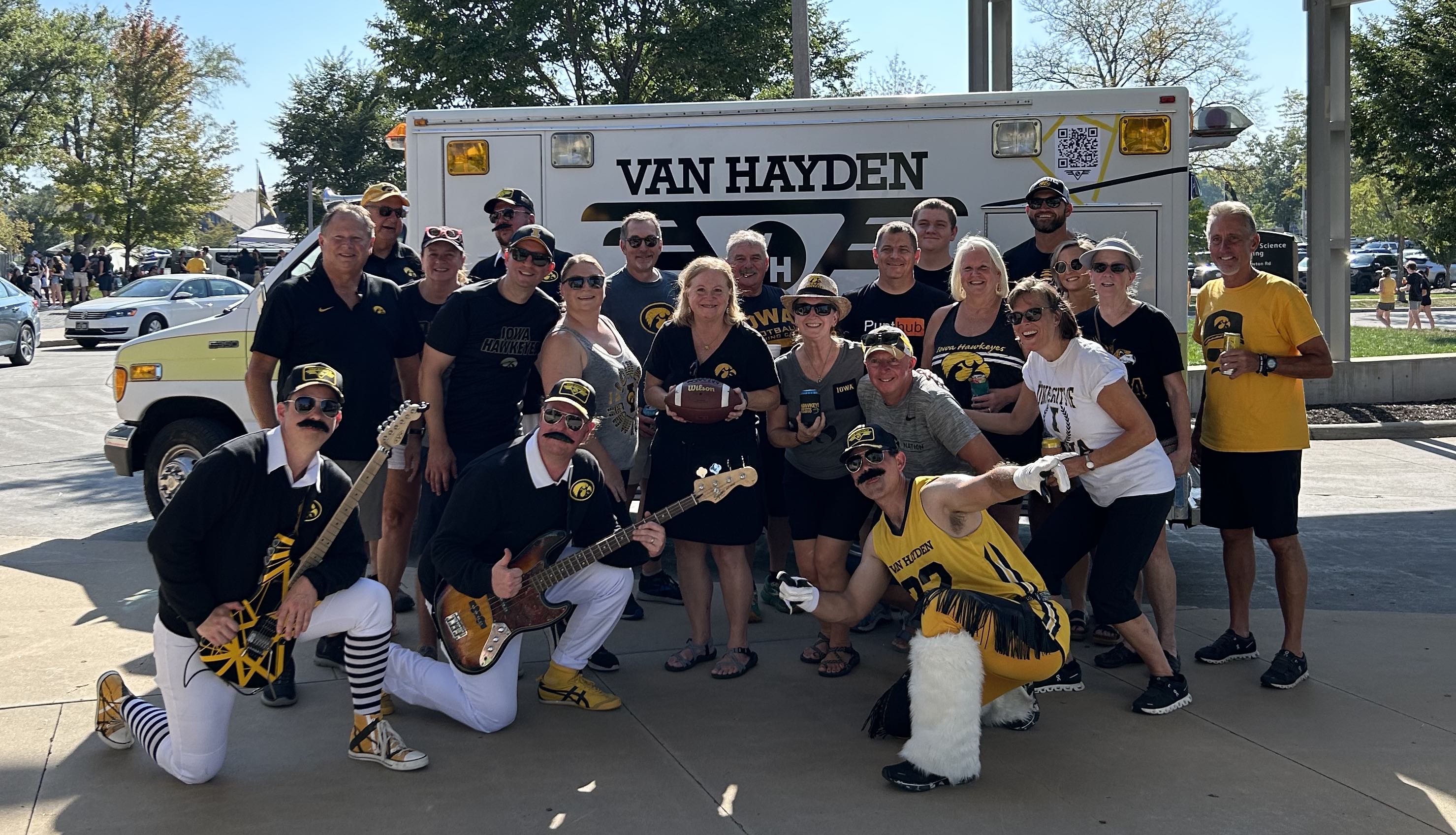 Van Hayden Band posing for a photo with Hawkeye fans in front of the Vanbulance at a tailgate for the Iowa vs. Michigan State game